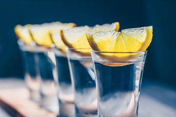 Close-up of selective focus on a row of glasses with tequila and lemon on the bar counter