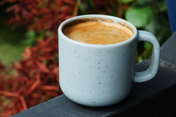 Hot black coffee in grey coffee cup served in a garden beside the river in an evening relax time with space for write wording, very good hot drink in a good environment for meet friend or lovers