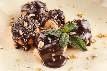 French profitroles with chocolate icing and mint leaves