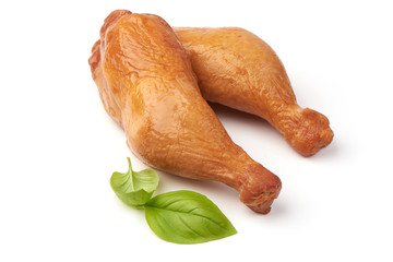 Smoked chicken drumsticks with basil leaves, isolated on white background.