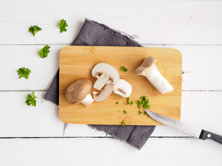 Champignons aufgeschnitten auf einem braunen Holzbrett auf einem weißen Tisch