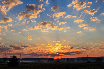 Beautiful sunrise over a green foggy meadow