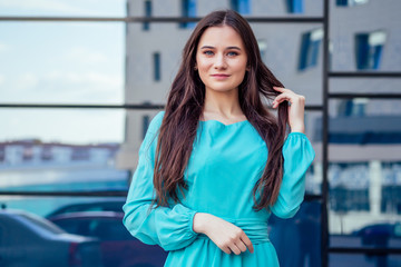 fashion portrait of young beautiful woman in blue color long flying dress walking down the street in new town