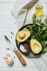 top view of ripe avocado, parsley and bowl with pepper on tray