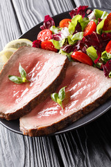 Freshly cooked rare beef steak with fresh vegetable salad close-up on a plate. vertical
