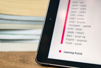 Learning Polish using a tablet with books in the background.