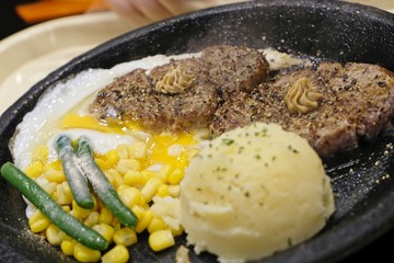 Japanese cuisine, grilled pork in steel hot plate served with sweet corn, mashed potato and cooked egg