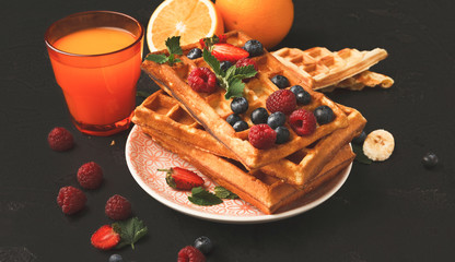 Belgian waffles with berries and fruits with juice glass