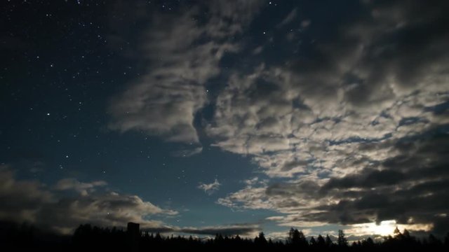 TimeLapse. Landscape of the night starry sky. Moving stars, floating clouds and moonrise.