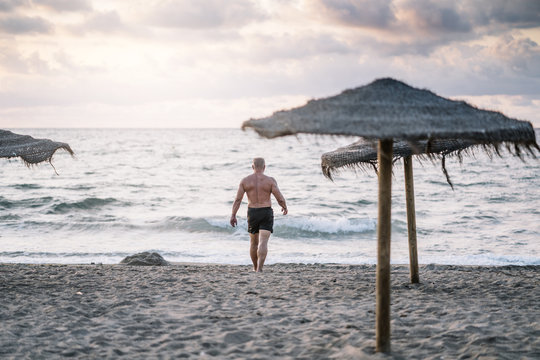 Strong old man walking on the beach