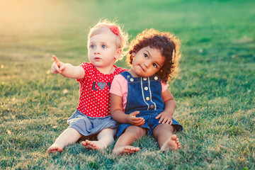 Group portrait of two cute adorable girls toddlers children sitting together. White Caucasian and...