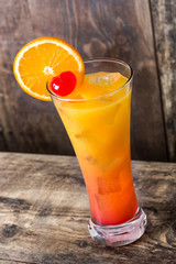 Tequila sunrise cocktail in glass on wooden table