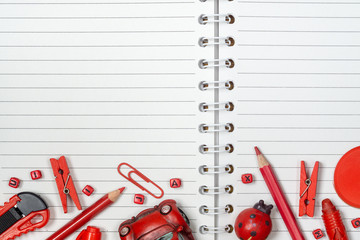Back to school, background concept. Red school supplies and toys on White notebook. Top view with...
