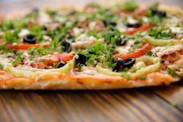 Preparation of homemade pizza with salami, mushrooms, olives, tomatoes and greens