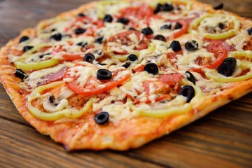 Preparation of homemade pizza with salami, mushrooms, olives, tomatoes and greens