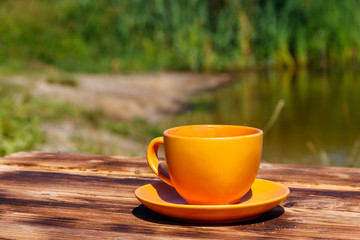 Cup of coffee on the wooden table near the river