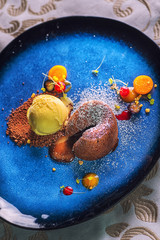 delicious sweet chocolate fondant with fruit served on blue plate, product photography for...