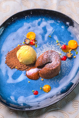 delicious sweet chocolate fondant with fruit served on blue plate, product photography for...