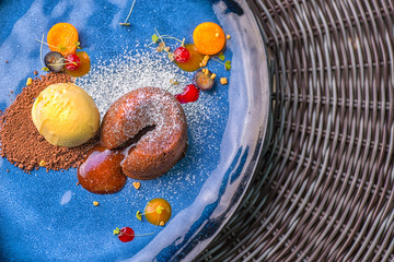 delicious sweet chocolate fondant with fruit served on blue plate, product photography for...
