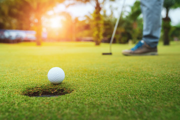 Golfer putting golf ball on the green golf, lens flare on sun set evening time, Pro Golf long...