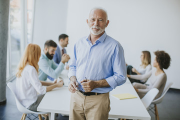 Obraz premium Senior businessman standing with digital tablet in his hand