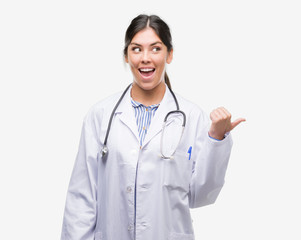 Young hispanic doctor woman pointing and showing with thumb up to the side with happy face smiling