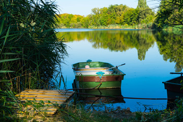 kleines Fischerboot an einem Holzsteg auf einem Weiher