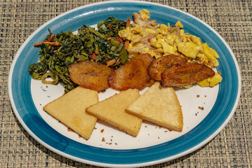 Typical Jamaican breakfast of fried bammy, friend plantain, ackee and sailfish, callaloo. These foods are also eaten for lunch or dinner.