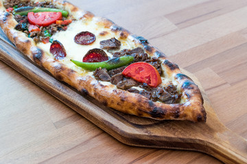 Turkish Mixed Pide with Minced Meat, Cheese, Sausage (Sucuk), Tomatoes and Red Pepper served with Salad and Pickles.