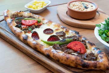 Turkish Mixed Pide with Minced Meat, Cheese, Sausage (Sucuk), Tomatoes and Red Pepper served with Salad and Pickles.