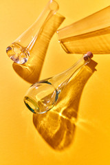 Three glass bottles empty on a yellow paper background with soft shadows and reflection.