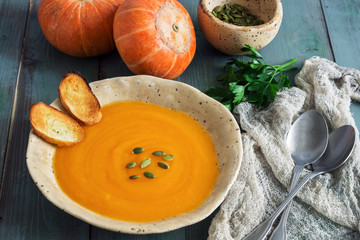 Pumpkin cream soup in a rustic style on a green wooden table. Selective focus.Healthy Eating