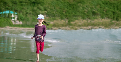 little Asian girl run play waves on the beach , run action
