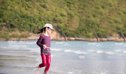 little Asian girl run play waves on the beach , run action