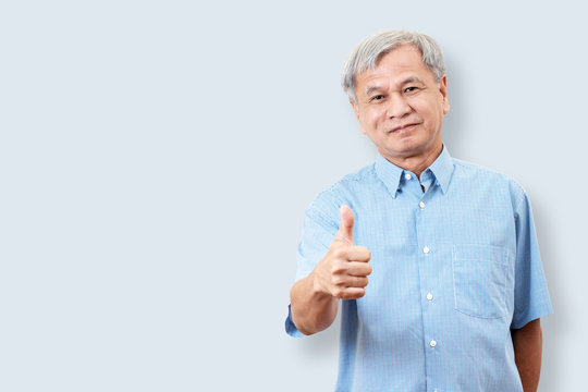Portrait of happy senior asian man gesture hand showing thumb up or good sign and looking at camera on isolated background feeling positive and satisfaction. Older mature male lifestyle concept.