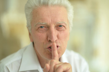 Portrait of a senior man with finger on lips