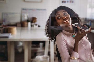 Businesswoman talking over mobile phone on loudspeaker while wor