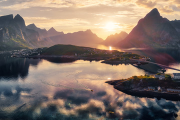 Aerial view of Reine with mountains and golden sunset in the background in Lofoten, Norway