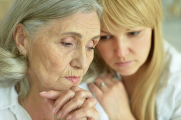 portrait of sad senior mother with adult daughter