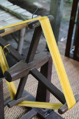 Closeup of traditional wooden spinning wheel used for making silk thread. Vertical view.