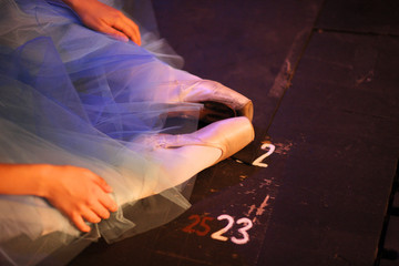 Ballerina in pointe shoes, sitting on the floor behind the scenes in the intermission of the ballet