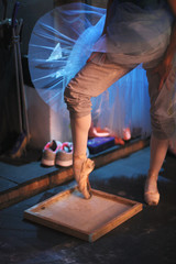 The ballerina rubs the toe of pointe shoes in a box with pounded rosin to prevent slipping