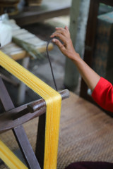 Closeup of traditional wooden spinning wheel used for making silk thread with woman's hand....