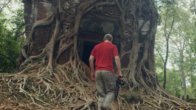 A photographer is exploring the root covered ancient Khmer temple of Prasat Bram in Cambodia's Preah Vihear province