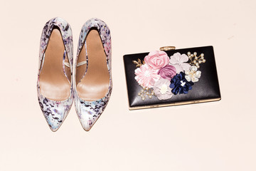beautiful women black clutch and floral pump hight heeled on pink background, party concept