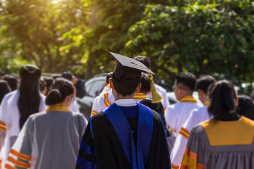 Soft focus of the crowded graduates celebrating commencement ceremony with joyful and fun. University graduation ceremony. Soft focus portrait of a graduate wearing black academic gown and cap.