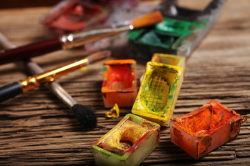 Artistic paintbrushes and watercolor paint  on the old wooden background