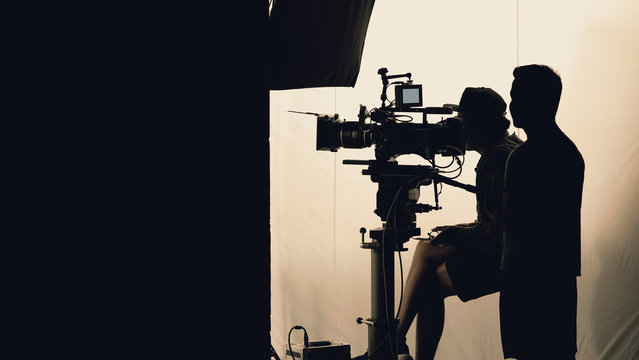 Video production behind the scenes which film crew team in silhouette shooting or recording tv movie commercial with professional equipment such as high definition 4k camera with monitor in studio