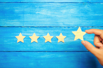 The businessman's hand holds the fifth star. A new star, achievement.The concept of the rating of...