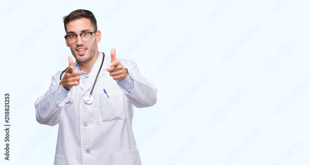 Poster Handsome young doctor man pointing fingers to camera with happy and funny face. Good energy and vibes.